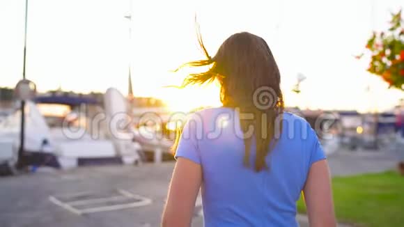 戴墨镜的女人在日落时带着很多游艇和船沿着码头走关门慢动作视频的预览图
