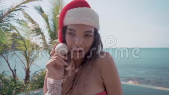 在游泳池附近的年轻女子戴着圣诞帽庆祝新年和圣诞节视频的预览图