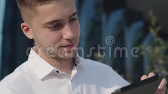 一位年轻商人在办公室外拿着平板电脑的画像视频的预览图