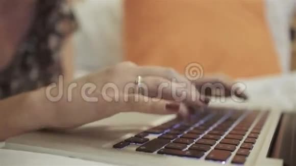年轻漂亮的女人躺在卧室的床上在笔记本电脑上打字视频的预览图