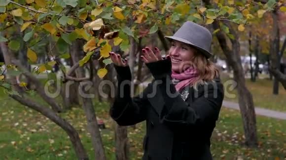 戴帽子的成年美女在秋天公园散步欢乐的秋游视频的预览图
