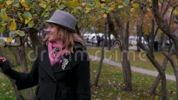 戴帽子的成年美女在秋天公园散步欢乐的秋游视频的预览图