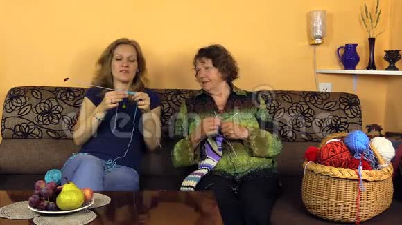 快乐的老奶奶和护士女孩在养老院的沙发上编织视频的预览图