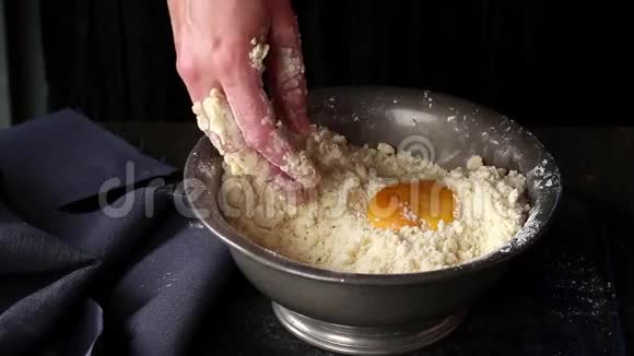 用女人的手在老式的金属碗里用老式的木桌上做酥皮面团视频的预览图
