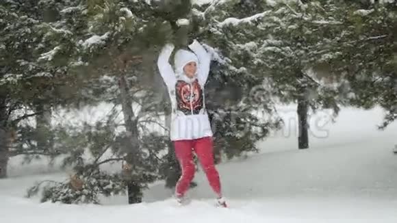 迷人的年轻女子在雪地里奔跑在雪地里摇动着雪枝在雪地里缓慢的运动中享受冬天视频的预览图