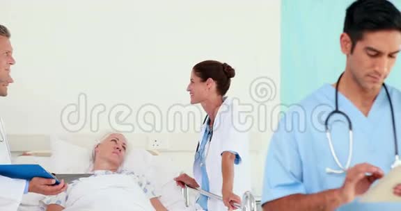 医生在看平板电脑而他的同事在和病人说话视频的预览图