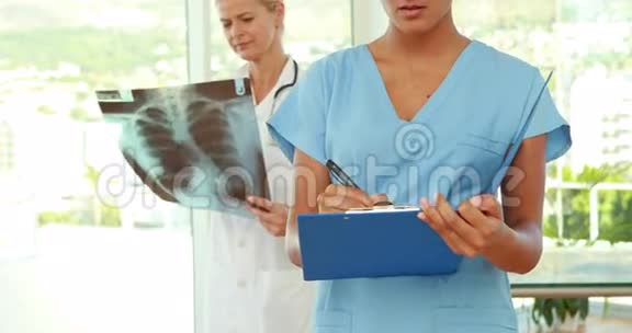 医生和她身后的同事在剪贴板上写字视频的预览图