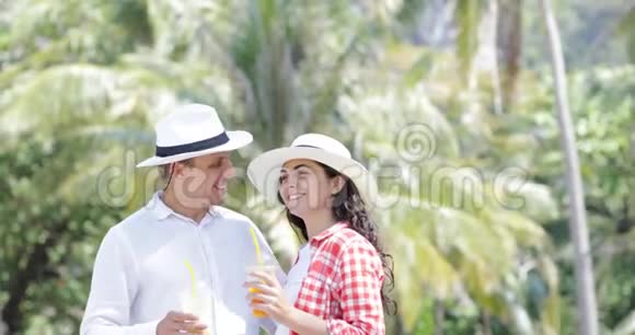 棕榈树下的夫妻谈饮汁热带度假的男女游客交流视频的预览图