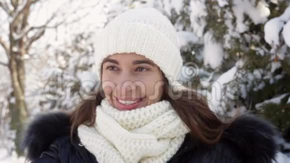 戴着针织帽子的漂亮女人正在冬天的花园里散步视频的预览图