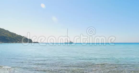 波浪降落在石滩上在地平线上的游艇清澈的蓝色海水视频的预览图