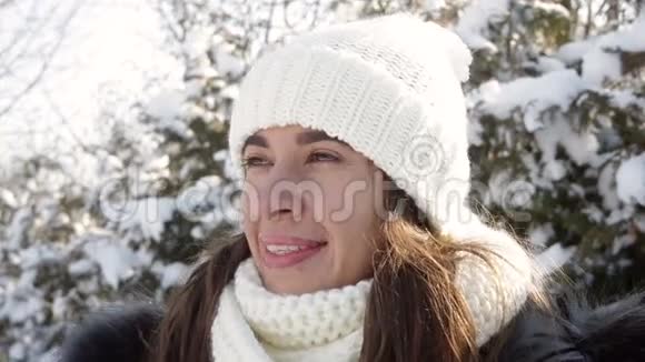 戴着针织帽子的漂亮女人正在冬天的花园里散步视频的预览图