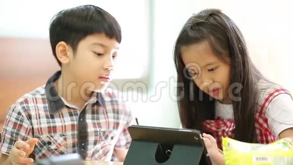 一群小亚洲孩子吃零食一起玩电脑平板电脑视频的预览图