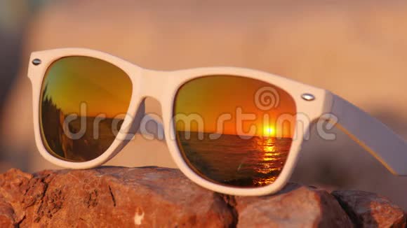 太阳落山在石头上的太阳眼镜上视频的预览图