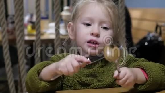 小女孩在咖啡馆里玩叉子和勺子视频的预览图