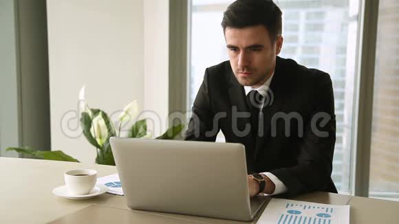 自信的年轻商人在办公室里用笔记本电脑看着相机视频的预览图