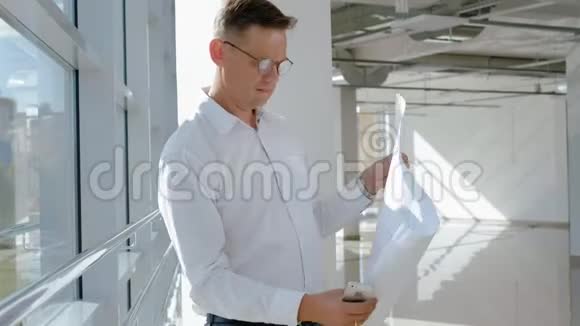 一个成熟的商人在窗口扫描一张纸上的图画视频的预览图