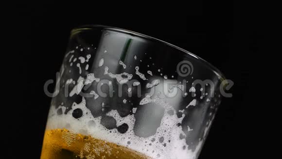啤酒倒入玻璃中泡沫泡在黑暗的背景下视频的预览图