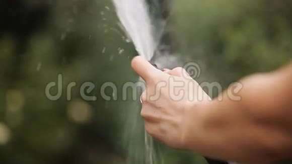 女孩的双手用软管浇灌花草视频的预览图