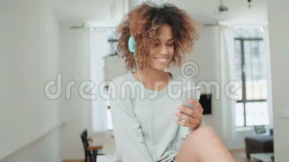 快乐而快乐的年轻女人享受音乐和拿着电话视频的预览图