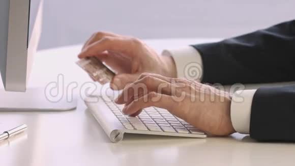 在网上购物时男性手拿着信用卡在键盘上视频的预览图