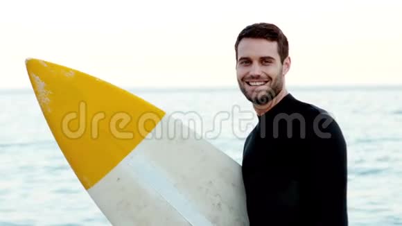 穿着湿衣服的男人用冲浪板打手势视频的预览图