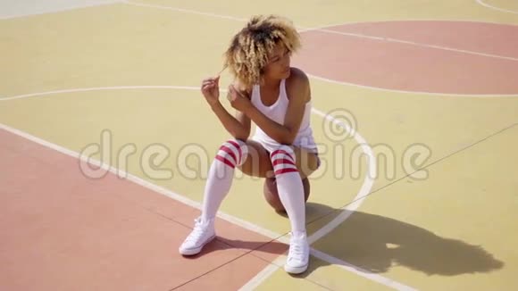 漂亮的女运动员坐在篮球上视频的预览图