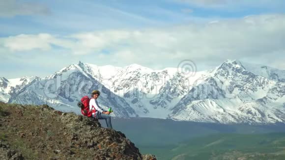 那个带着红色背包的旅行者的女人坐着看雪山视频的预览图