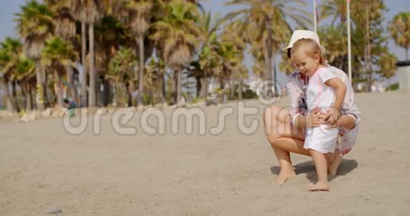 阳光明媚的一天妈妈和女儿在海滩上视频的预览图