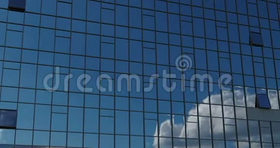 神圣的平稳的相机运动在办公楼前的窗户反射阳光蓝天与白色蓬松的云4k视频的预览图