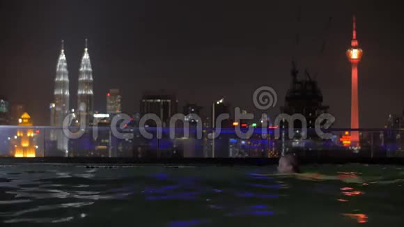 晚上在吉隆坡屋顶游泳池放松的女人视频的预览图