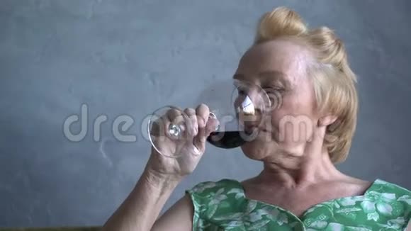 快乐的老妇人喝着酒看着电视笑着视频的预览图