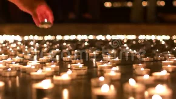 女人把蜡烛放在其他蜡烛之间视频的预览图