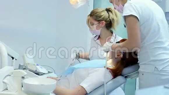 戴面具和戴手套的牙医解释即将到来的治疗然后开始检查使用视频的预览图