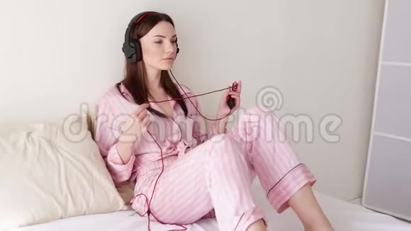 在床上戴着大耳机听音乐的女人视频的预览图