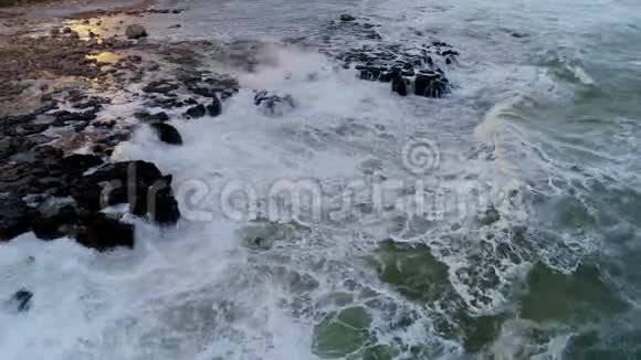 空中无人驾驶飞机俯瞰岩石海岸线海浪拍打视频的预览图