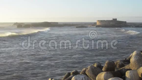 日落时的古堡和巨大的海洋海浪视频的预览图