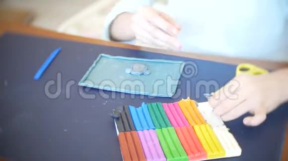 坐在桌子旁的女孩从彩色模型塑料中画出不同的图形艺术造型的发展视频的预览图