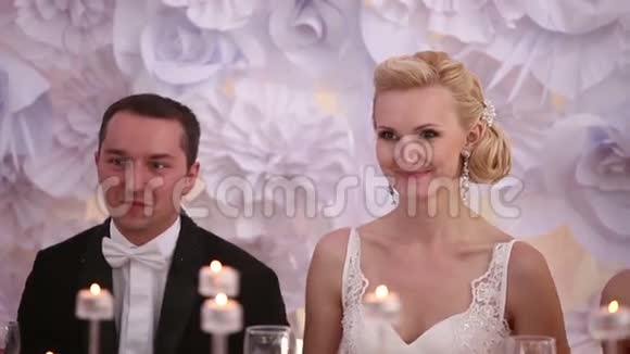 新婚夫妇在她的婚礼上坐在一张桌子旁鼓掌微笑着靠近视频的预览图