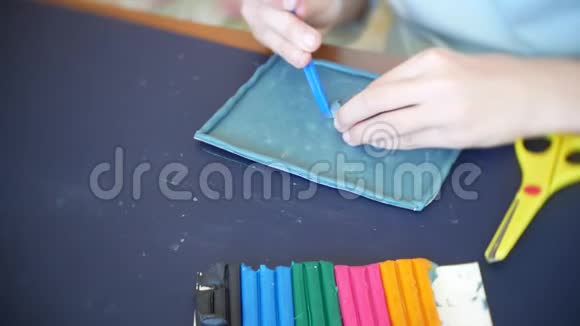 坐在桌子旁的女孩从彩色模型塑料中画出不同的图形艺术造型的发展视频的预览图