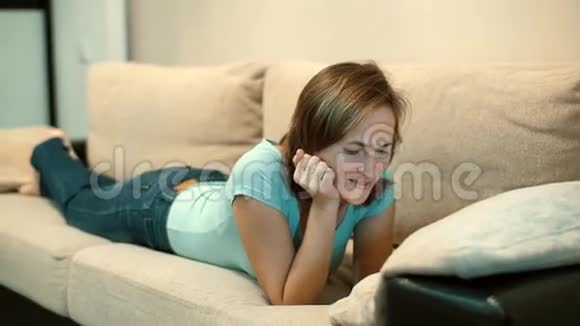 躺在沙发上看智能手机视频的女人视频的预览图