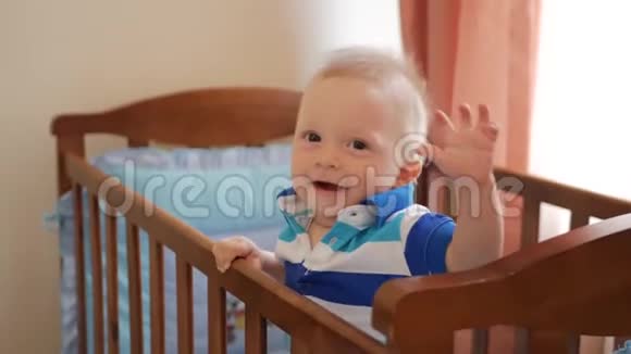 婴儿站在家里的床上婴儿男孩站在床上的肖像宝贝的眼睛在找妈妈视频的预览图