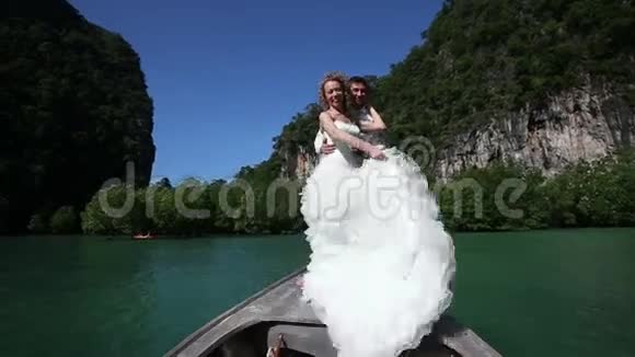 金发新娘的姿势和扣子新郎站在长尾船上视频的预览图