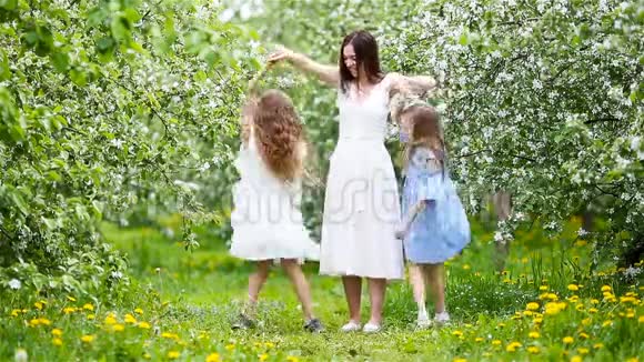 可爱的小女孩和年轻的母亲在盛开的樱花园美丽的春天视频的预览图