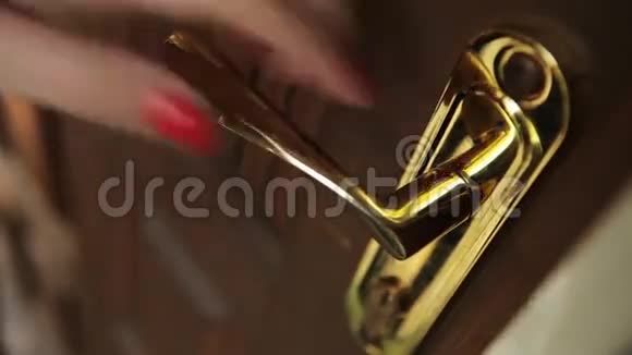 女人手里拿着红色的指甲推着金色的门把手走了进去日视频的预览图