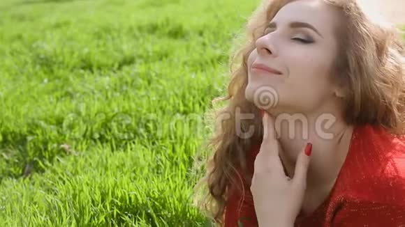 幸福微笑的女人躺在绿草上享受生活年轻的女人在春天公园户外玩得很开心视频的预览图