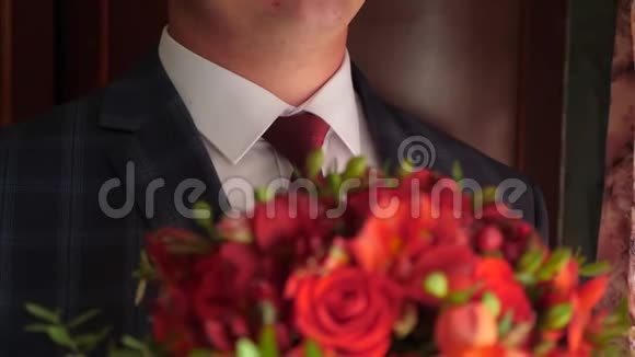 穿着红色领带和白色衬衫的男人手中捧着一束美丽的红玫瑰特写视频的预览图