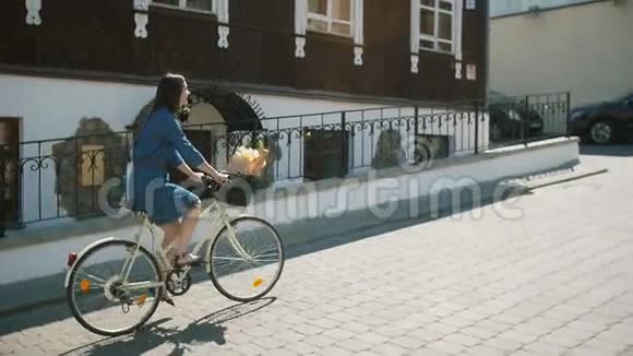 快乐的女孩穿着连衣裙骑自行车和探索城市慢莫稳定的镜头视频的预览图