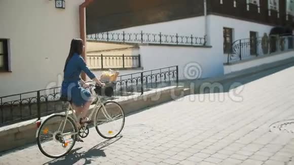 快乐的女孩穿着连衣裙骑自行车和探索城市慢莫稳定的镜头视频的预览图