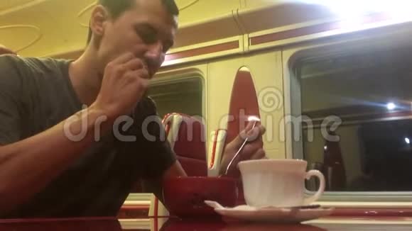 男人晚上在火车餐厅吃汤铁路猫喝咖啡男子乘坐火车概念旅程旅行视频的预览图