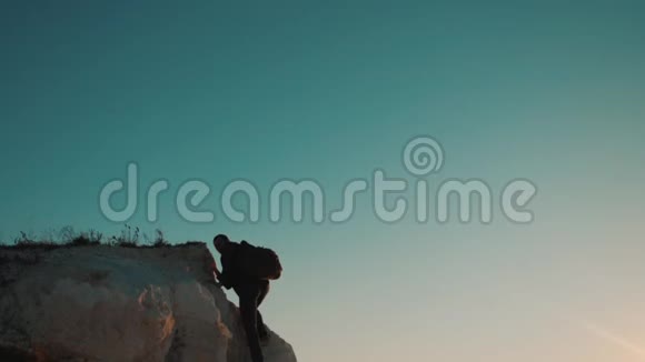 一位游客在日落探险时爬上山顶的剪影剪影生活方式视频的预览图